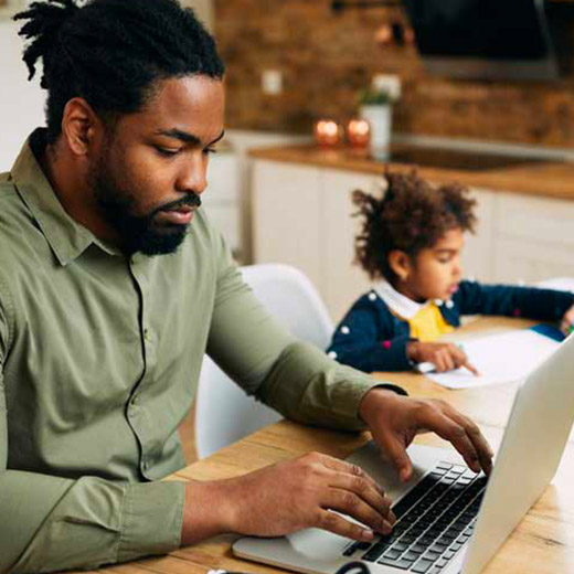 homme et son ordinateur avec ses enfants à côté