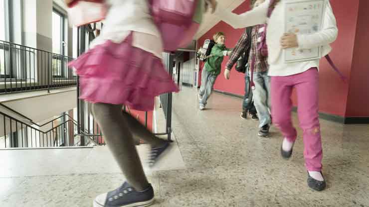 Dans cette photographie, des élèves se déplacent en courant dans les couloirs et escaliers d’un établissement scolaire.