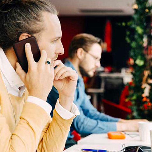 homme au téléphone devant son bureau