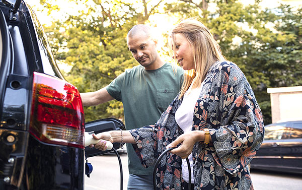 pack auto responsable - deux adultes près d'une voiture électrique